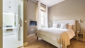 Une chambre à coucher avec un lit, une télévision, une lampe de chevet et une fenêtre.