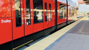 A red trolley at a station with a tiled platform and a covered waiting area.