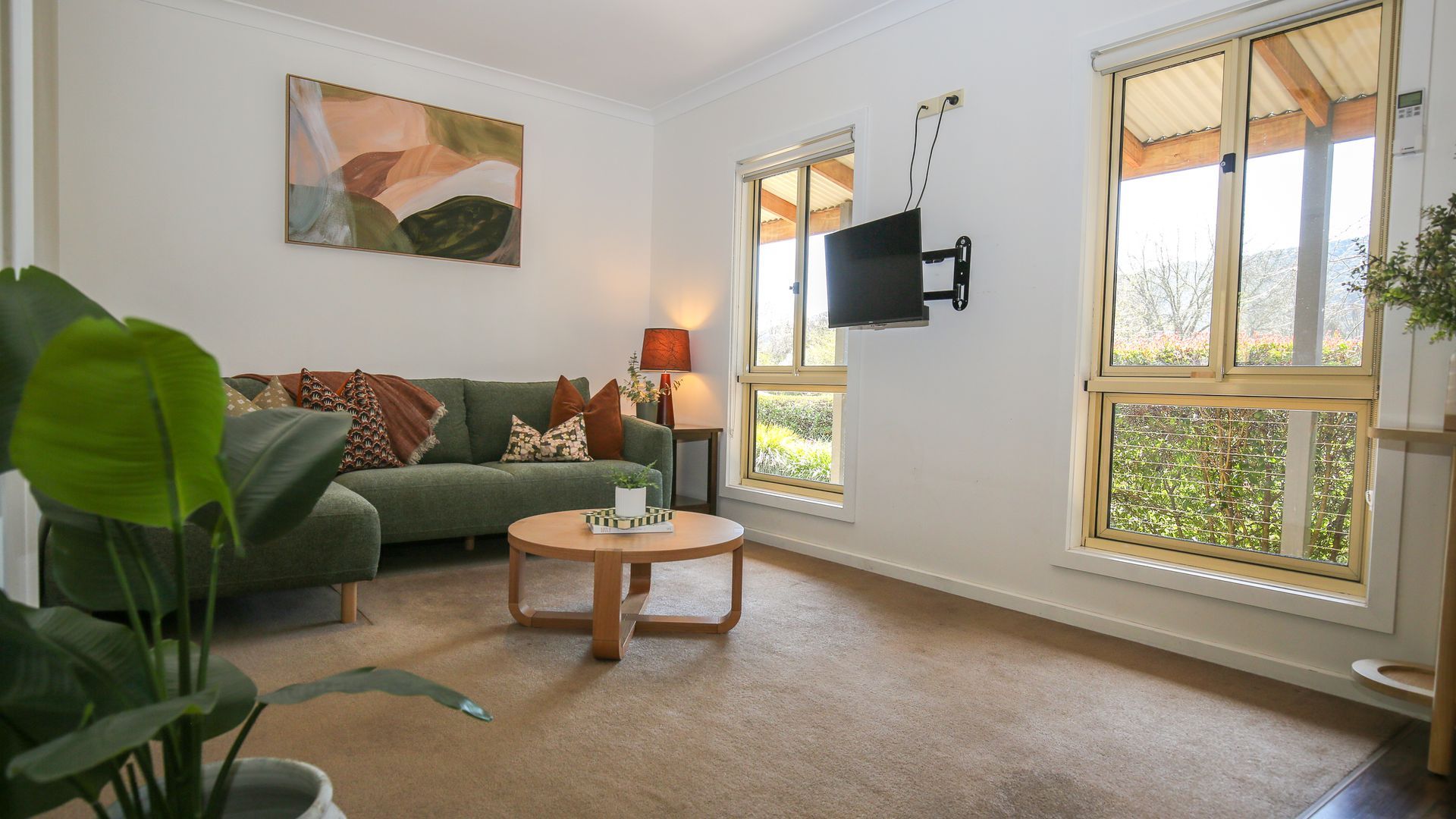 Un salon avec un canapé vert, une table basse ronde et un tableau accroché au mur.