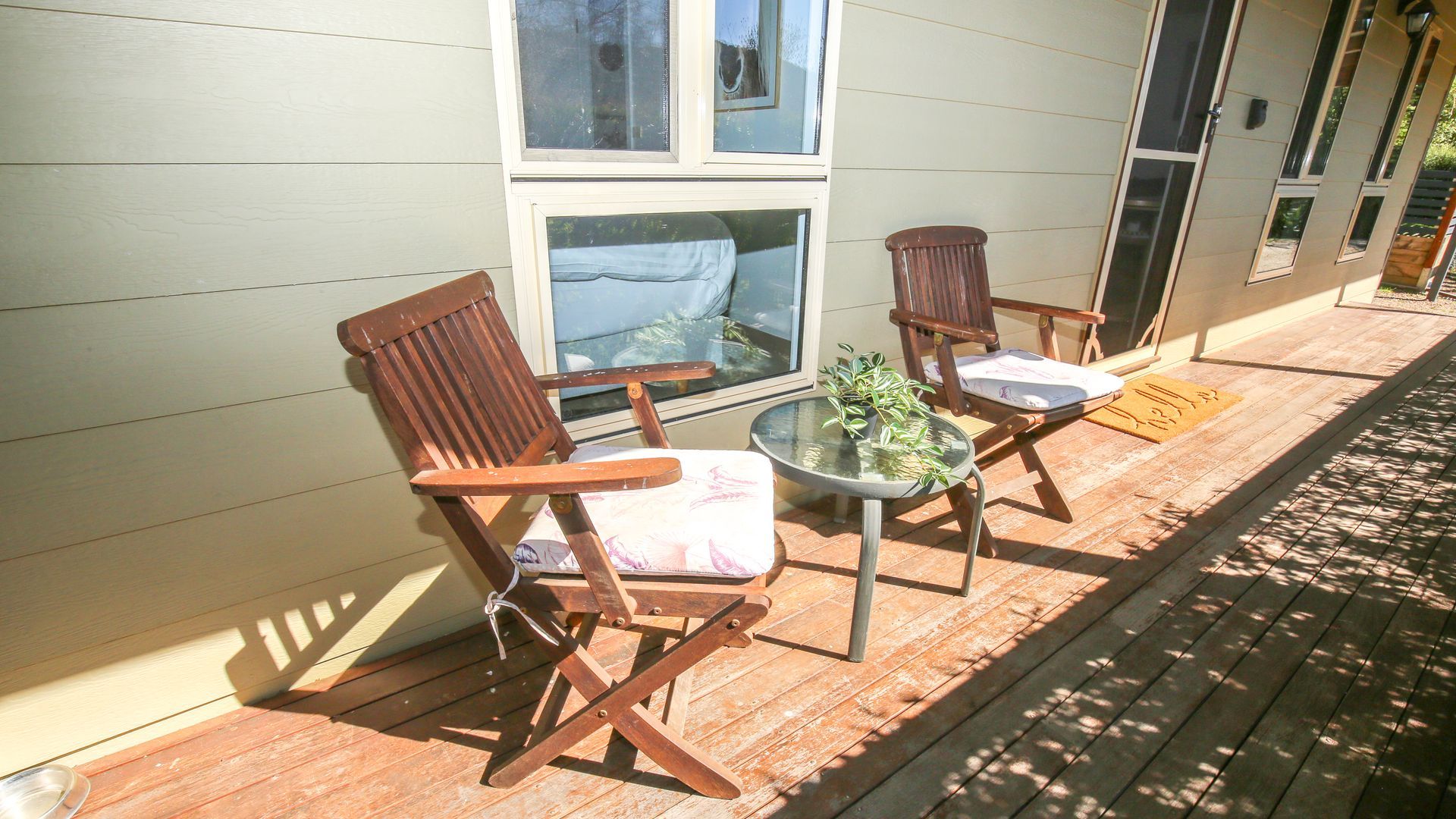 A wooden deck with two rocking chairs and a small table with a plant.