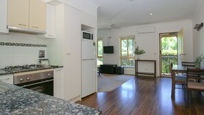 Un'ampia cucina con piano cottura a gas, mobili bianchi e un'ampia finestra.
