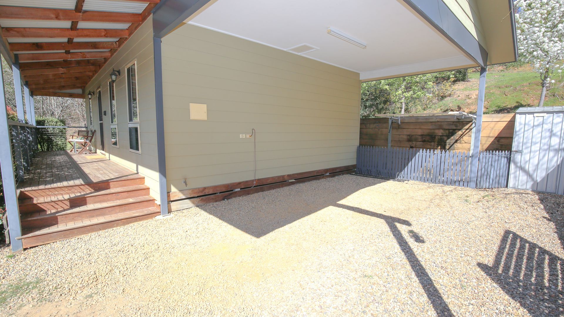 Un patio couvert avec une terrasse en bois et des marches menant à la maison.