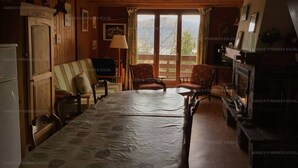 A cozy room with a large bed, a wooden wardrobe, a fireplace, and a view through a window. - 3* Chalet for 8, fireplace, parking, free shuttle (Les Angles)