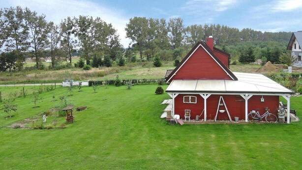 A red barn with a white roof, surrounded by a well-maintained grassy field and trees.