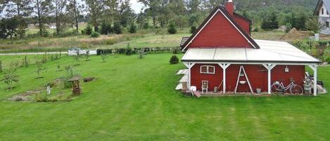 A red barn with a white roof, surrounded by a well-maintained lawn and trees.