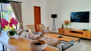 A modern living room with a sofa, coffee table, and TV stand. - Villa Ataya (Sukasada)