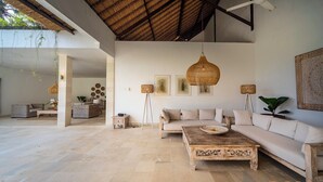 A spacious living area with a wooden coffee table, beige sofas, and hanging rattan lamps. - Truly a Luxury Hidden Jewel in Paradise! Private, Romantic and Breathtaking! (Tumbu)