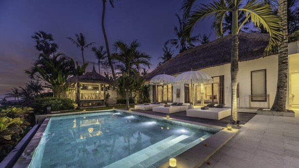 A poolside area with a thatched-roof structure, outdoor seating, and a well-lit pool. - Truly a Luxury Hidden Jewel in Paradise! Private, Romantic and Breathtaking! (Tumbu)