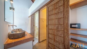A bathroom with a large mirror, a wooden vanity, a sink, and a sliding door leading to a shower area. - Truly a Luxury Hidden Jewel in Paradise! Private, Romantic and Breathtaking! (Tumbu)