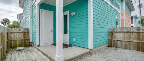 A turquoise house with a white porch and a wooden deck.