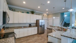A modern kitchen with white cabinets, granite countertops, a stainless steel refrigerator, and a built-in dishwasher. - Sea Escape! Stunning Gulf-View Retreat with Private Pool (Panama City Beach)