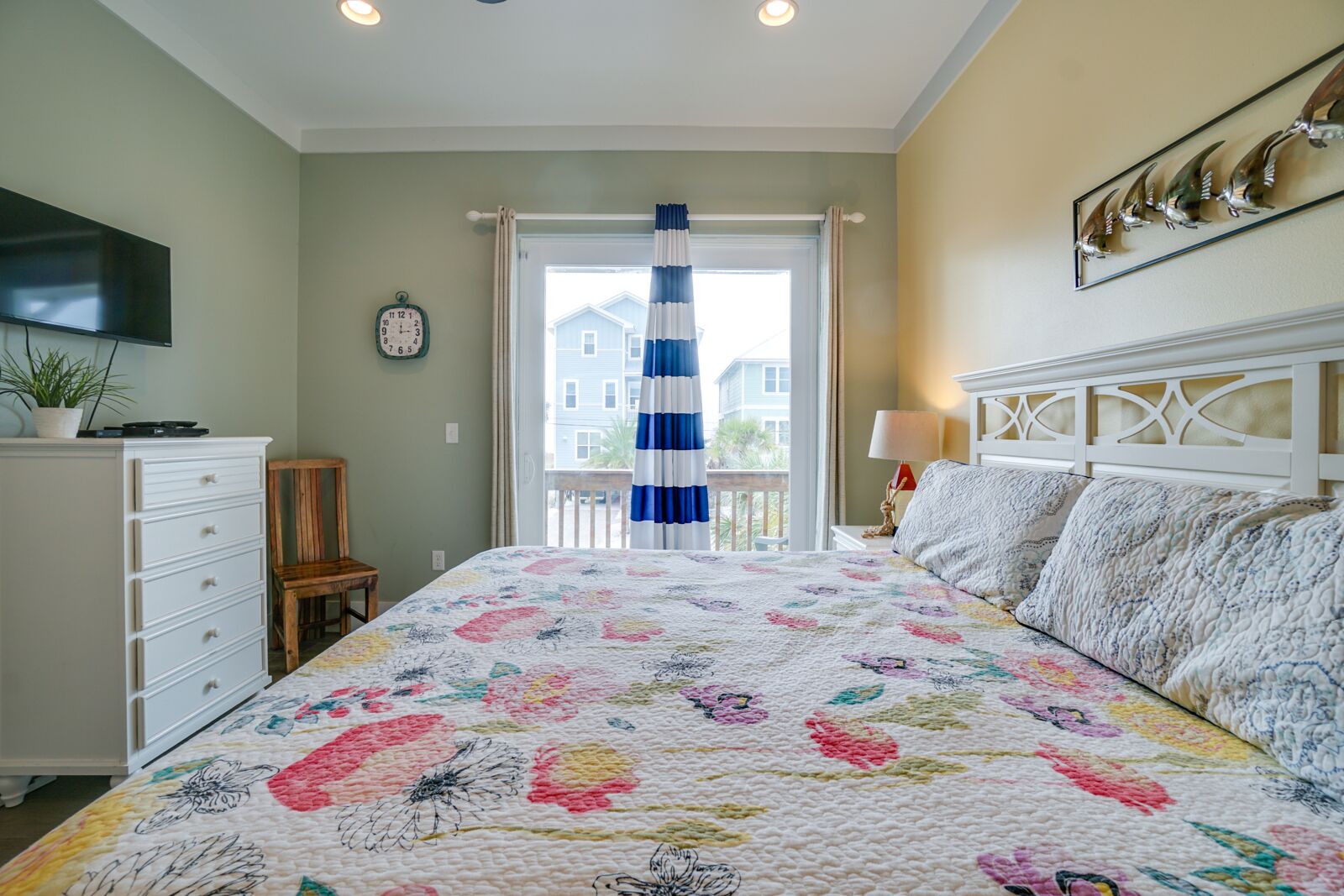 Une chambre à coucher avec un grand lit, une commode, une chaise, une horloge et une fenêtre avec des rideaux.