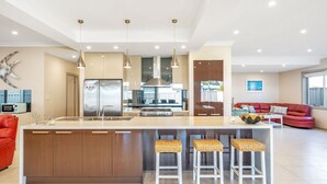 Une cuisine moderne avec un îlot central, des appareils en acier inoxydable et un canapé en cuir rouge dans l’espace salon.