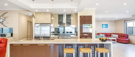 A modern kitchen with a central island, stainless steel appliances, and a red leather sofa in the living area.
