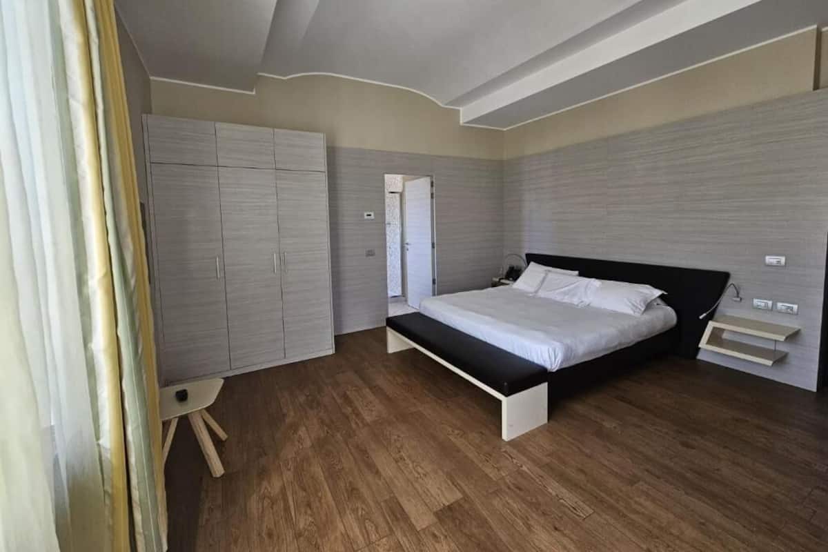 A bedroom with a bed, a wardrobe, and a bench.