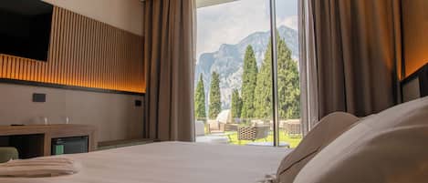 Une chambre d’hôtel dotée d’un grand lit, d’un téléviseur à écran plat fixé au mur, d’un petit bureau avec une chaise et offrant une vue sur les montagnes grâce à de grandes fenêtres.