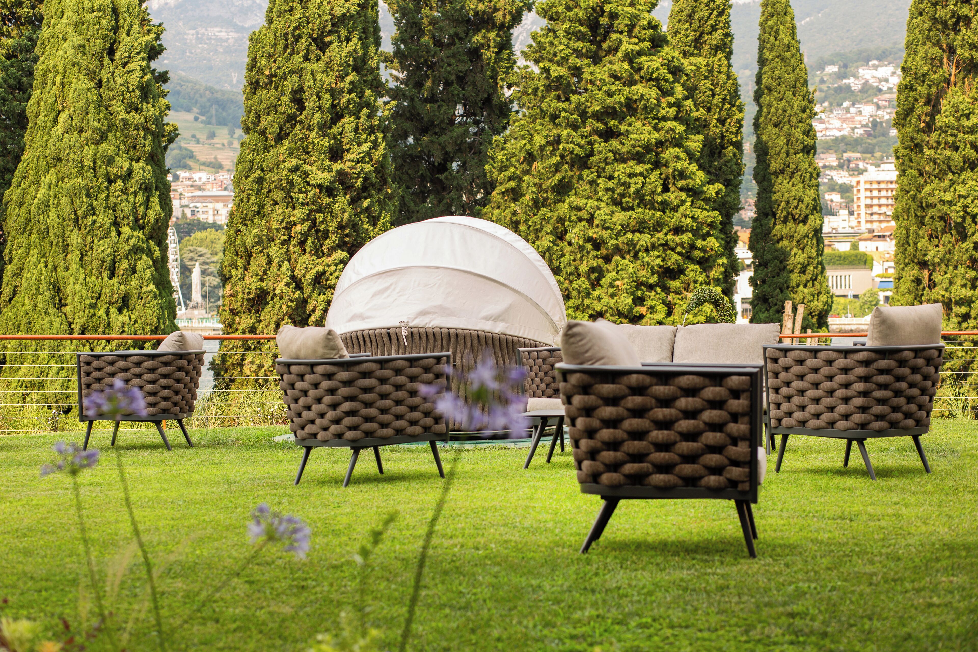 A grassy outdoor seating area with four cushioned chairs and a white canopy.