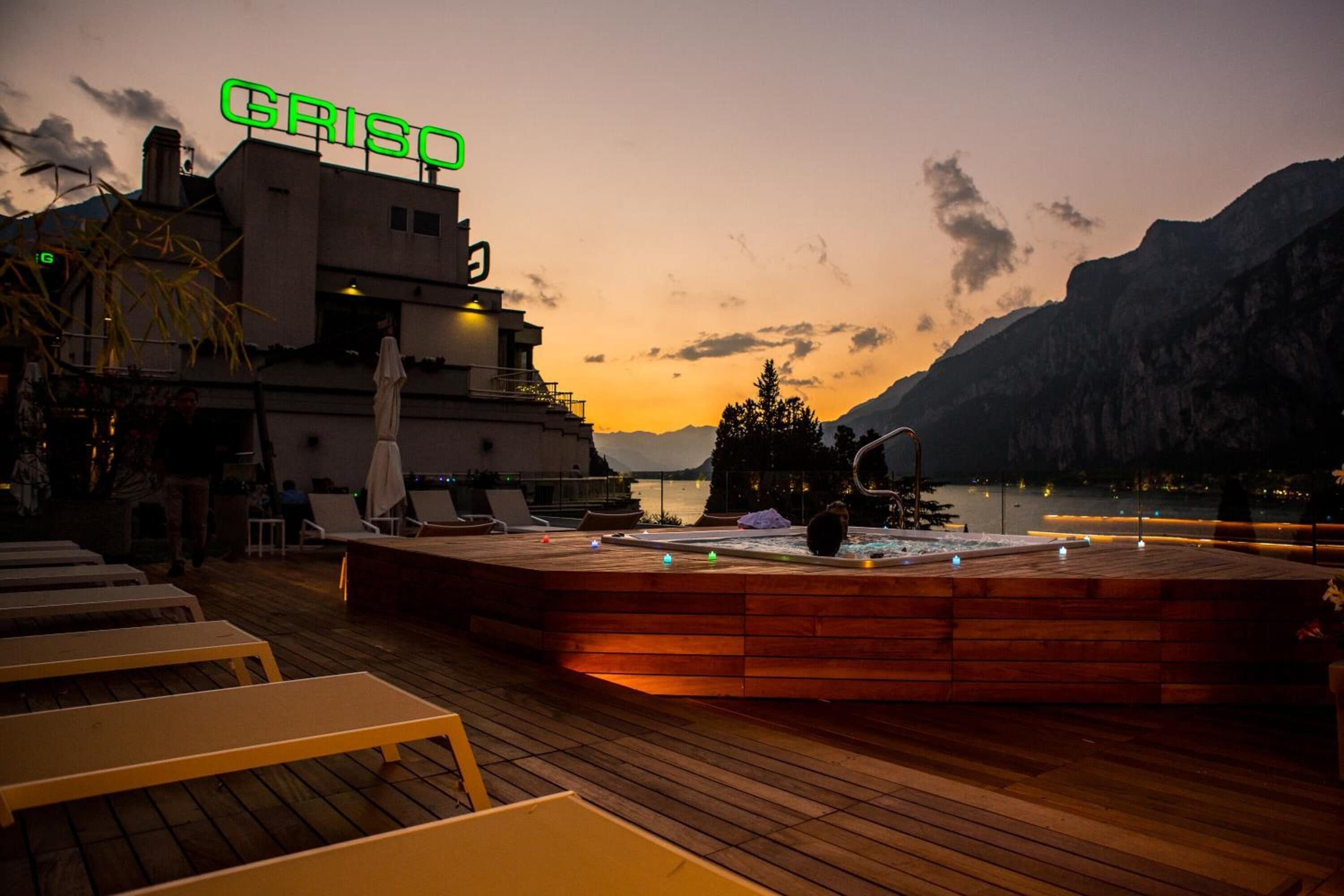 Una terraza de madera con sillones de descanso, un jacuzzi y un edificio con un letrero que dice "GRISCO".