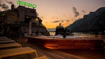 A wooden deck with lounge chairs, a hot tub, and a building with a sign reading "GRISCO".