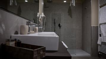 A modern bathroom with a large sink, a shower, and a towel rack.