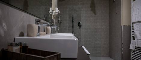 Un baño moderno con un lavamanos grande, una ducha y un perchero para toallas.