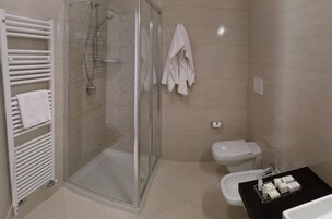 Un baño moderno con ducha de vidrio, inodoro blanco y lavamanos negro con artículos de aseo.