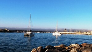 Una marina con veleros amarrados, una costa rocosa y un cielo despejado.