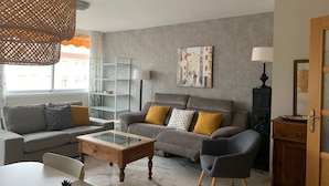 Una sala de estar moderna con un sofá, sillones, una mesa de centro y una estantería.