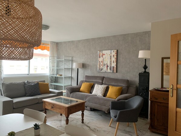 A modern living room with a sofa, armchairs, a coffee table, and a bookshelf.