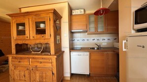 Une cuisine de taille réduite, dotée de meubles en bois, d’un four encastré et d’un four à micro-ondes.