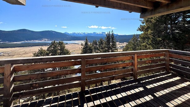 Une terrasse en bois avec un banc donnant sur un paysage montagneux.