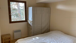 Une chambre à coucher avec un lit, une fenêtre, une armoire et un radiateur.