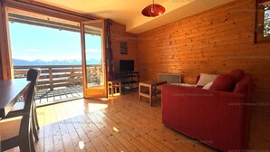 Un chalet confortable avec des murs en bois, un canapé rouge, une table à manger et un téléviseur.