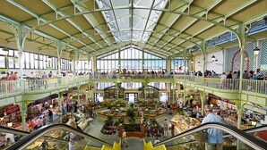 Un mercado interior de varios niveles con escaleras mecánicas, barandas de vidrio y distintos puestos.