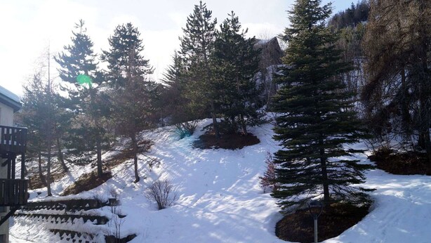 A snow-covered landscape with a building on the left and a steep slope with trees on the right. - Bright studio in Pra Loup 1500 for 4/5 people, easy ski lift access (Pra-Loup)