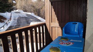 A table with a blue tablecloth and a fruit-themed design, placed on a wooden deck overlooking a snowy road. - Bright studio in Pra Loup 1500 for 4/5 people, easy ski lift access (Pra-Loup)