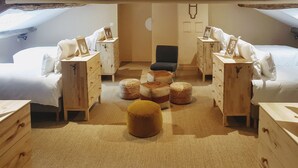 Un acogedor dormitorio en el ático con dos camas, muebles de madera y una zona de estar central.