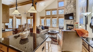 A spacious living area with a large island, wooden beams, stone walls, and multiple windows. - Awesome Townhome just off Main Street in Frisco!! (Frisco)