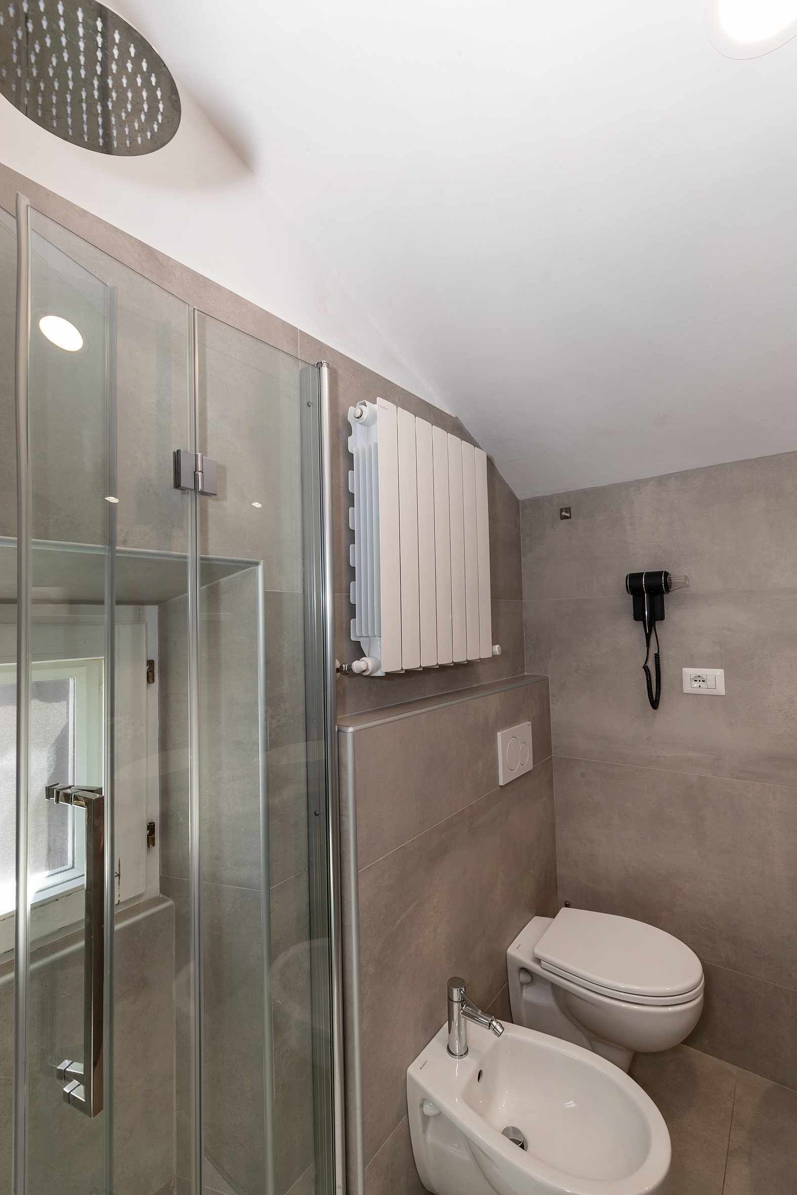 Een moderne badkamer met een douchecabine van glas, een wit wastafelmeubel en een toilet.