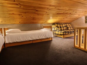 A wooden interior with a bed, a chair, and a small table.