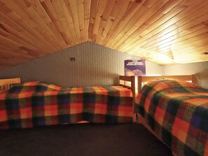 Una habitación con dos camas, techo de madera y un cartel de cumpleaños.