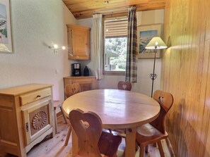 A wooden dining table with heart-shaped chairs, a wooden cabinet, a coffee maker, and a lamp.