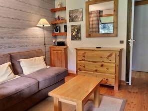 Ein gemütliches Wohnzimmer mit einem braunen Sofa, einem Holzschrank und einem kleinen Tisch.