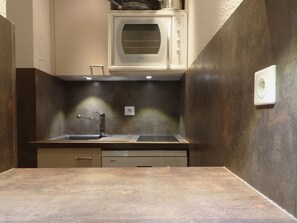 A compact kitchen with a built-in microwave, stainless steel sink, and a Bosch dishwasher.