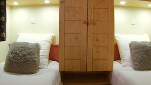 Una habitación con dos camas, cada una con un cojín mullido y un armario de madera en el centro.