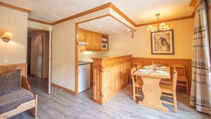 Una habitación acogedora con una mesa de comedor de madera, un sofá y una zona de cocina con armarios de madera y un refrigerador.