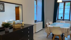 A modern room with a dining table, chairs, a dark wooden dresser, a potted plant, and a clock on the wall. - 3-bedroom/two-bathroom house in the countryside (Bezange-la-Grande)