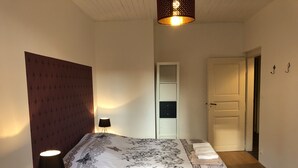 A bedroom with a bed, a bedside lamp, a wardrobe, and a door. - 3-bedroom/two-bathroom house in the countryside (Bezange-la-Grande)