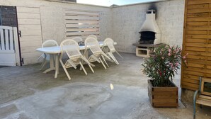 A patio with a round table and chairs, a wooden bench, a potted plant, and a stone chimney. - 3-bedroom/two-bathroom house in the countryside (Bezange-la-Grande)