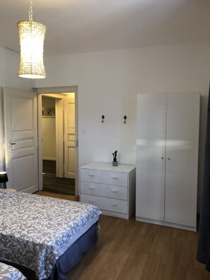 A bedroom with a bed, a dresser, a wardrobe, and a hanging light fixture.